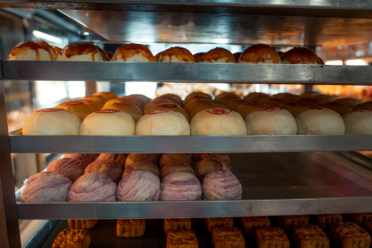 Assorted traditional Asian buns and pastries displayed on bakery shelves, inviting and fresh.